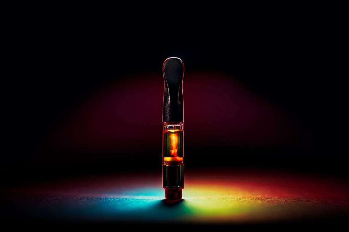 Cannabis vape cartridge under rainbow lighting