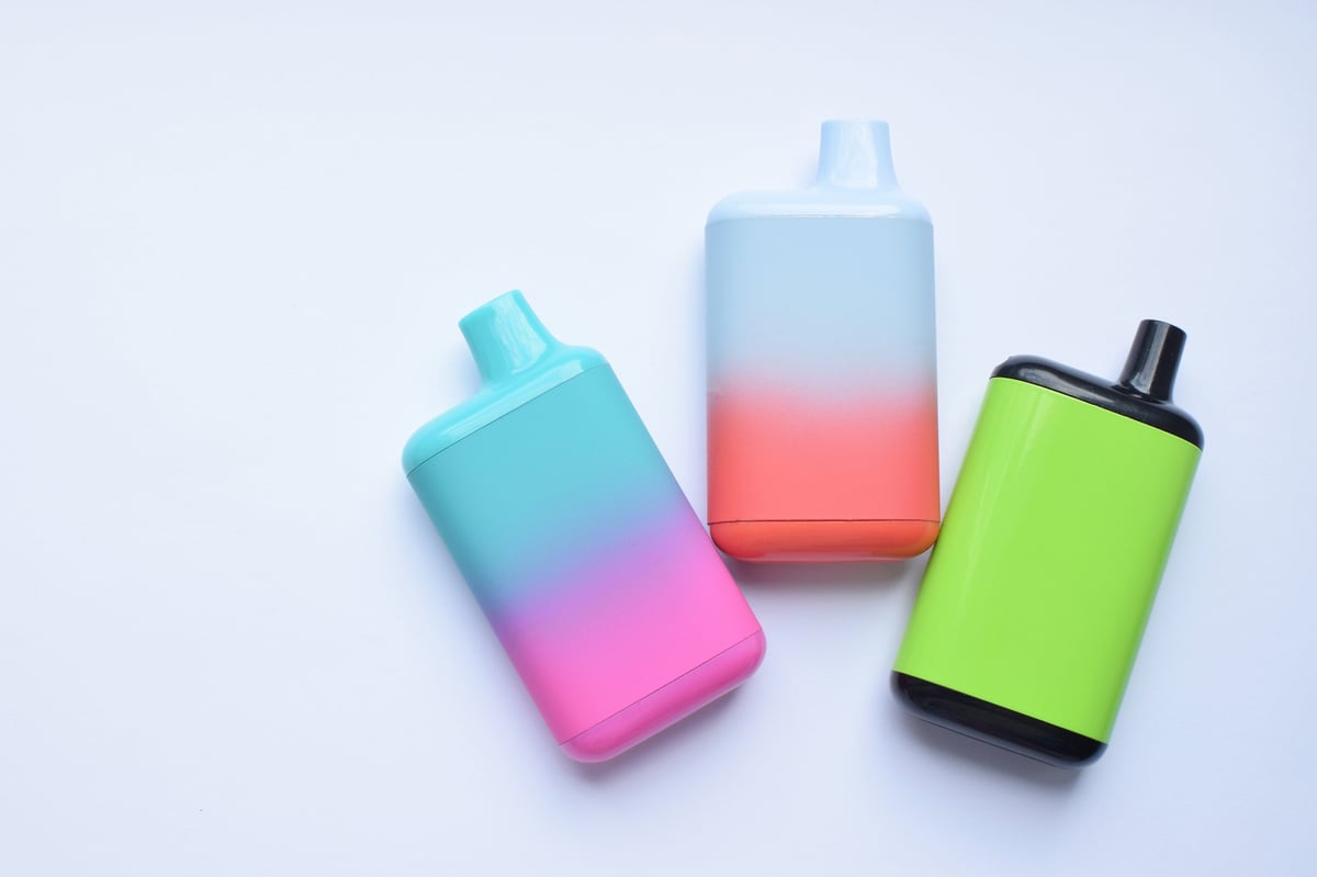 Several colourful disposable vape devices on a light table