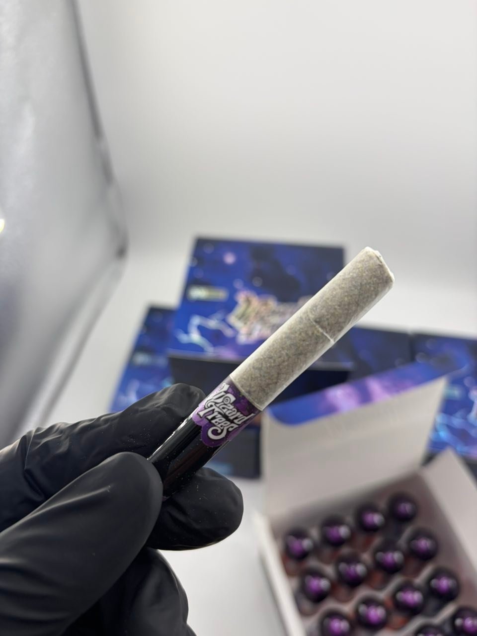 Hand in a black glove holding a pre-rolled cannabis joint